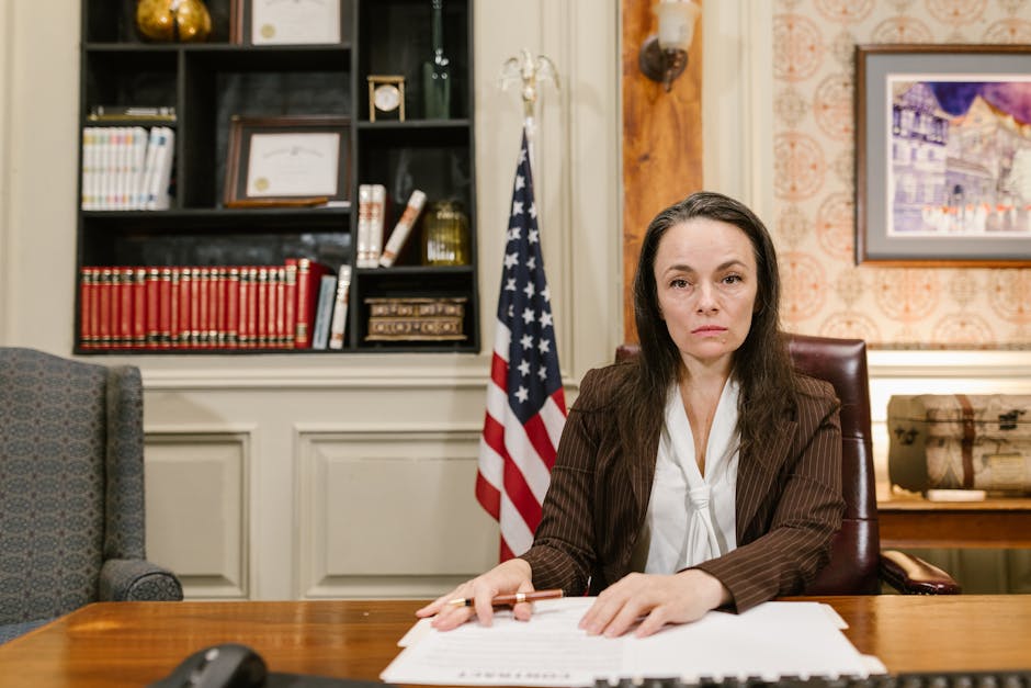 Confident female lawyer at her desk in a law office with legal books