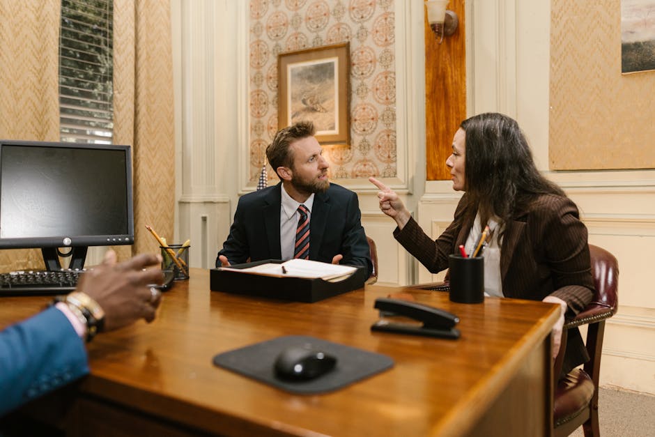 Professionals engaged in a serious discussion inside a law office with a computer on the desk